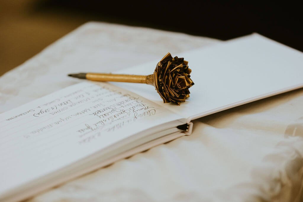 Up close image of wedding guest book and floral pen at intimate woodland wedding