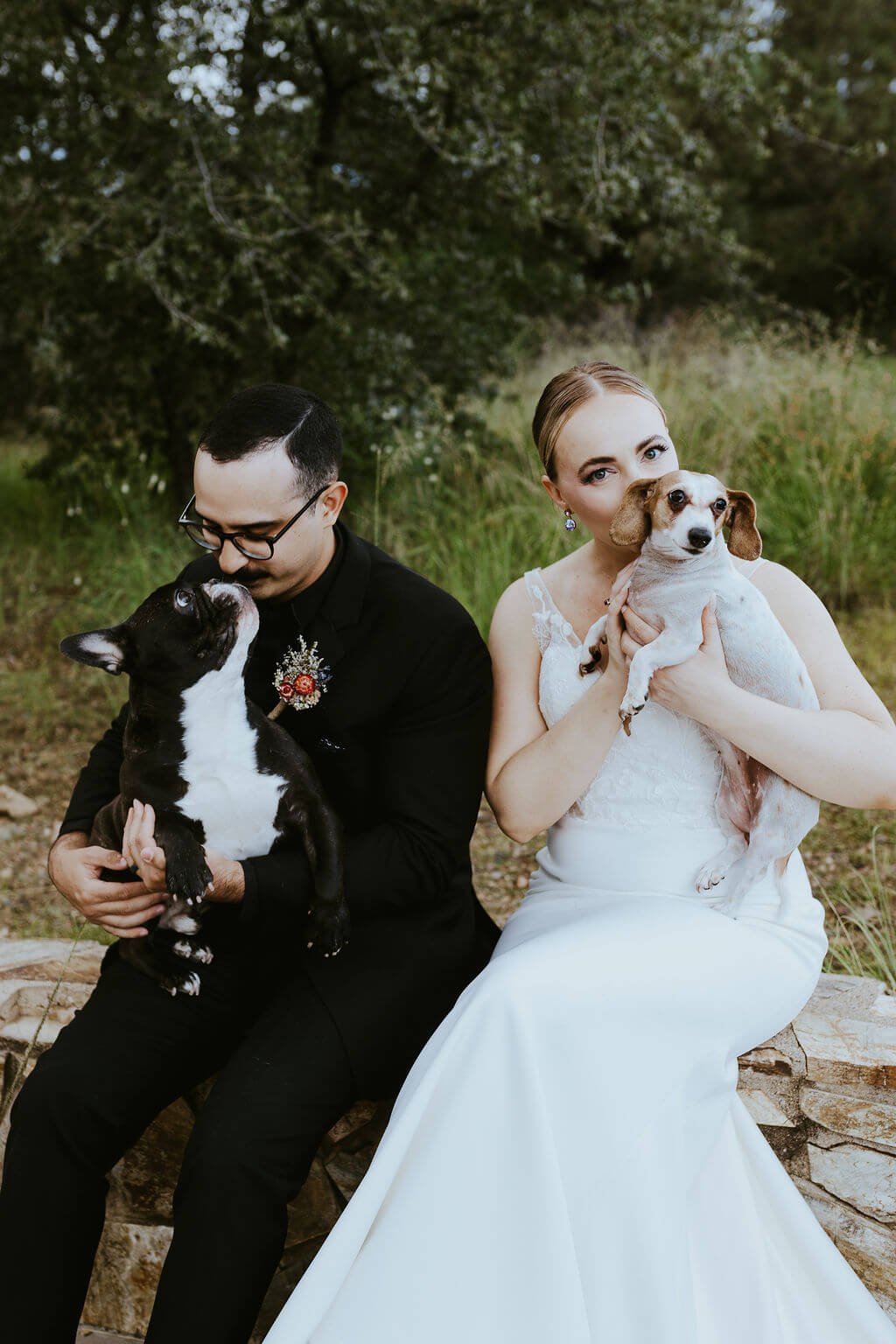 Bride and groom holding their two dogs outside at intimate woodland wedding