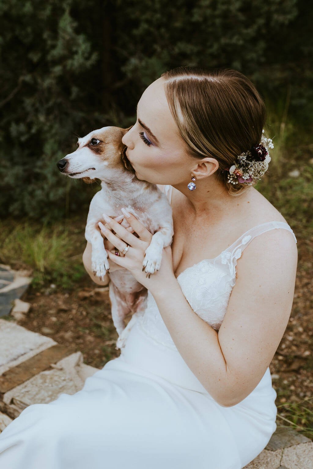 Bride kissing her Dachshund at woodland wedding