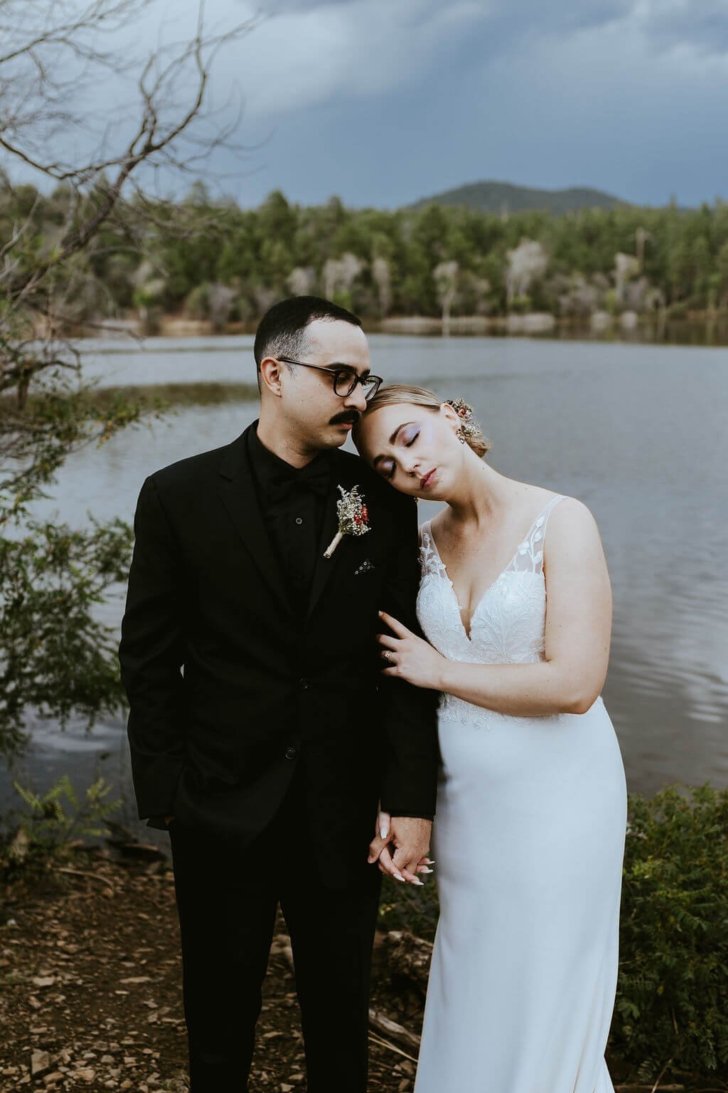 Bride and groom standing in front of a lake