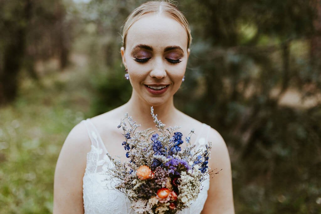 Up close image of bride with floral bouquet in the woods