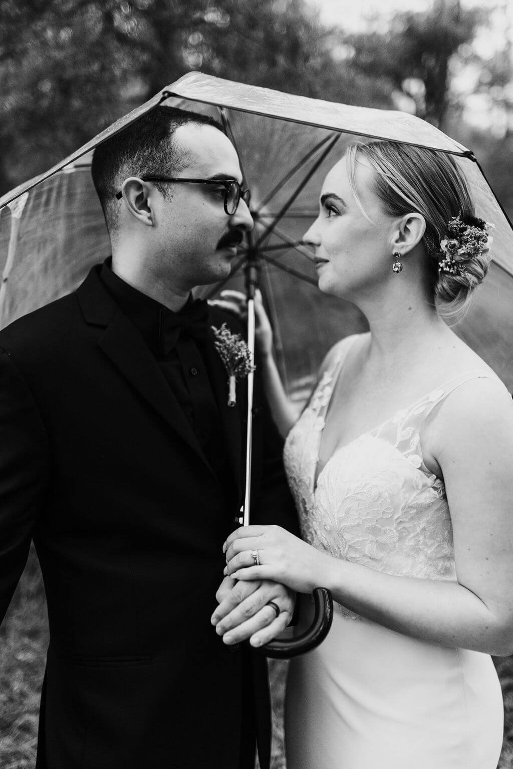 Black and white photo of bride and groom under an umbrella