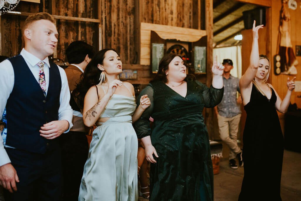 Wedding guests dancing with groom in barn at Southern California wedding