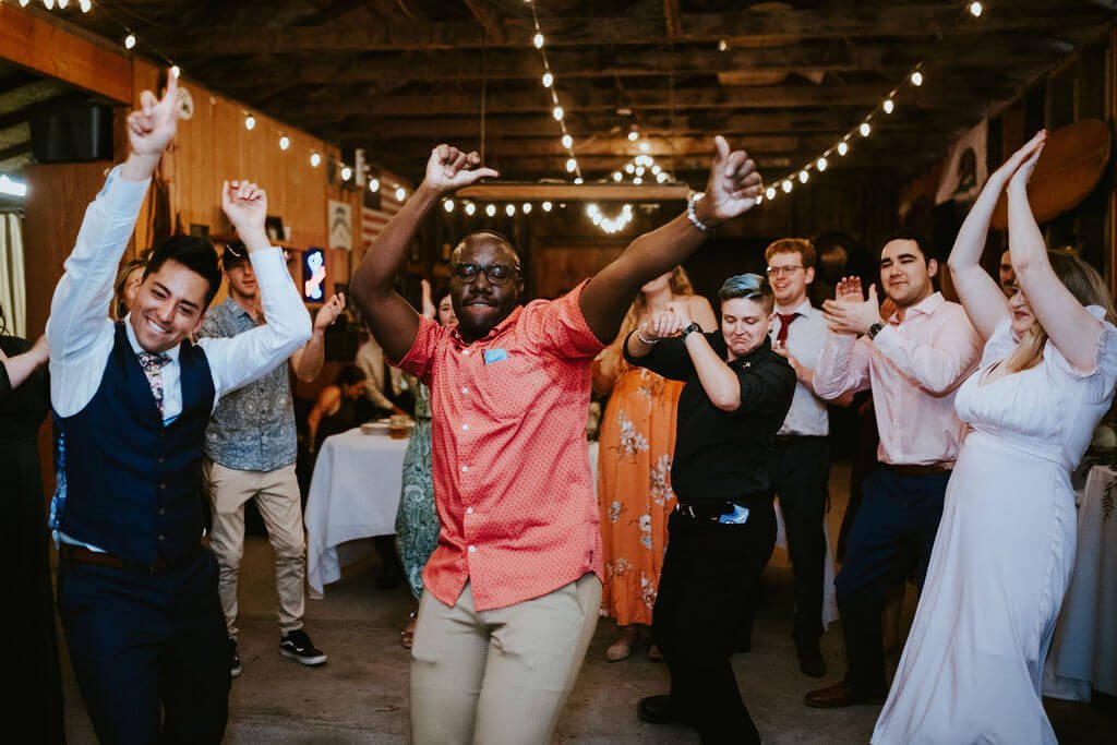 Wedding guests dancing with groom in barn at Southern California wedding