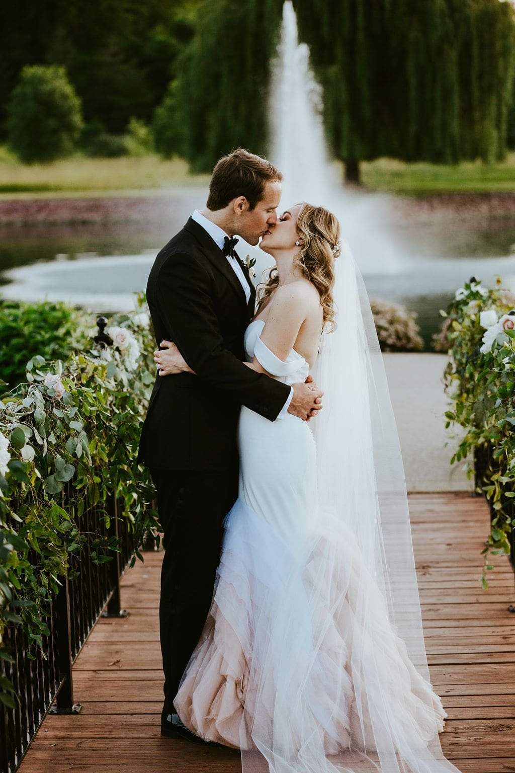 Bride and groom kiss in front of the fountain at Orchard Ridge Farms wedding