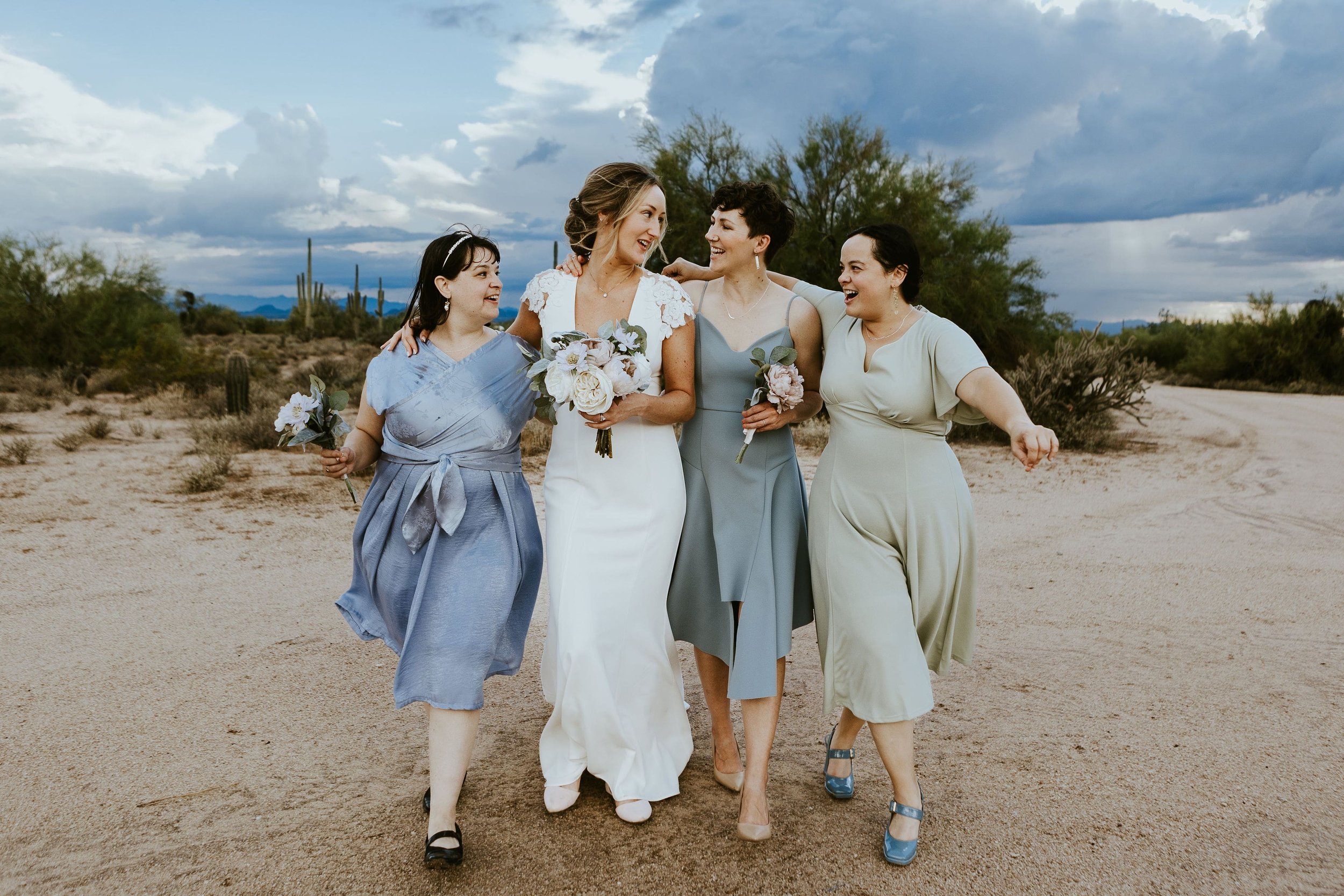 Bride walks arm in arm with bridal party at desert foothills wedding in Arizona