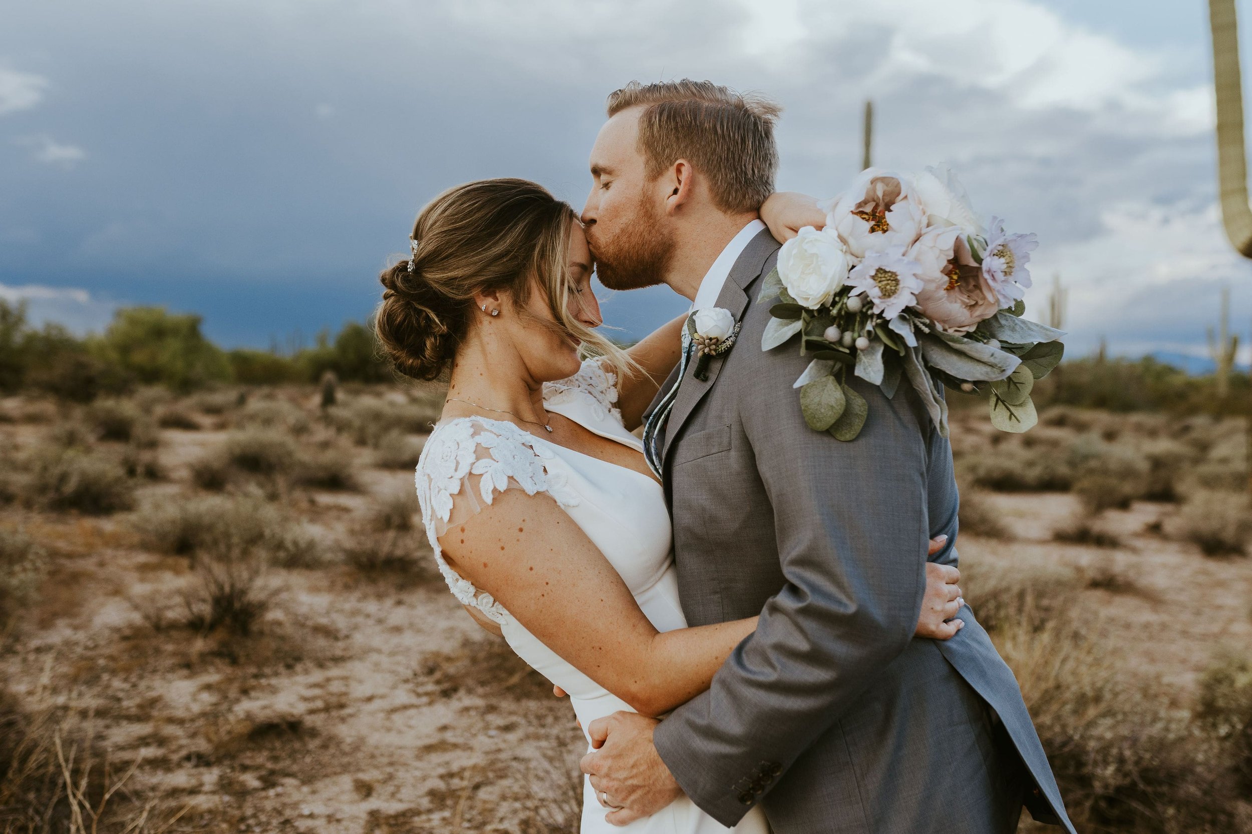 Groom kisses bride on the forehead during desert foothills wedding photos