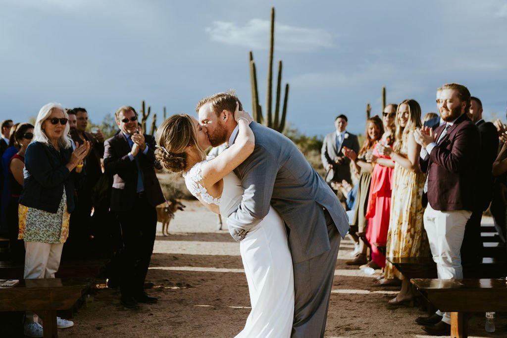 Bride and groom kiss at the end of the aisle after their fall wedding ceremony in Arizona