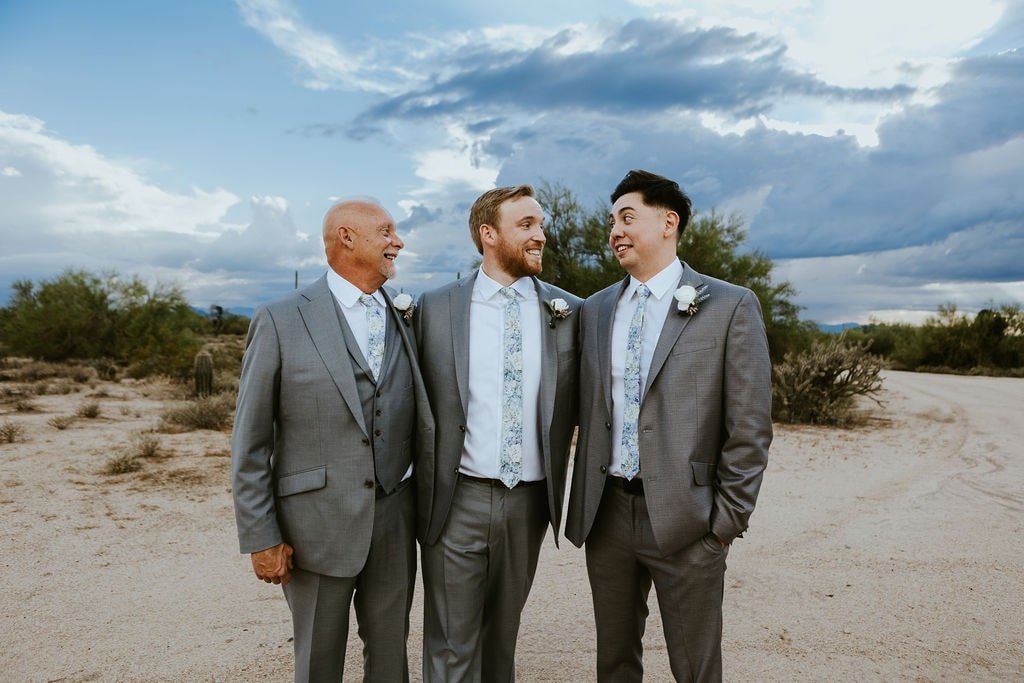 Groom and two groomsmen in gray suits with white shirts and blue ties