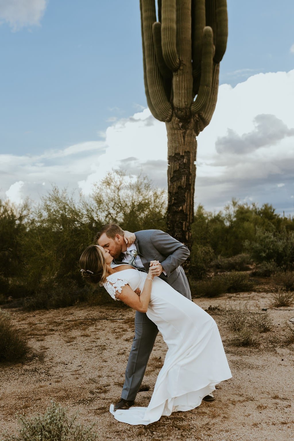 Groom dips bride for a kiss during desert foothills wedding photos