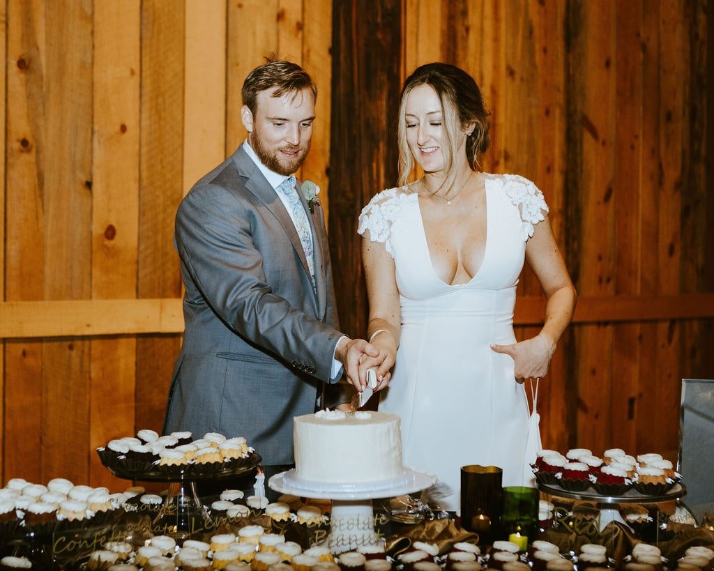 Bride and groom cut into white frosted wedding cake at their fall wedding in Arizona