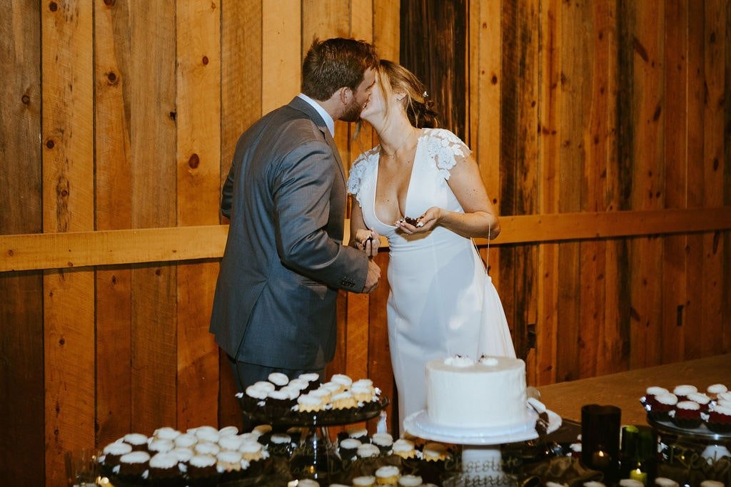 Bride and groom kiss after cutting their white wedding cake at their desert foothills wedding reception