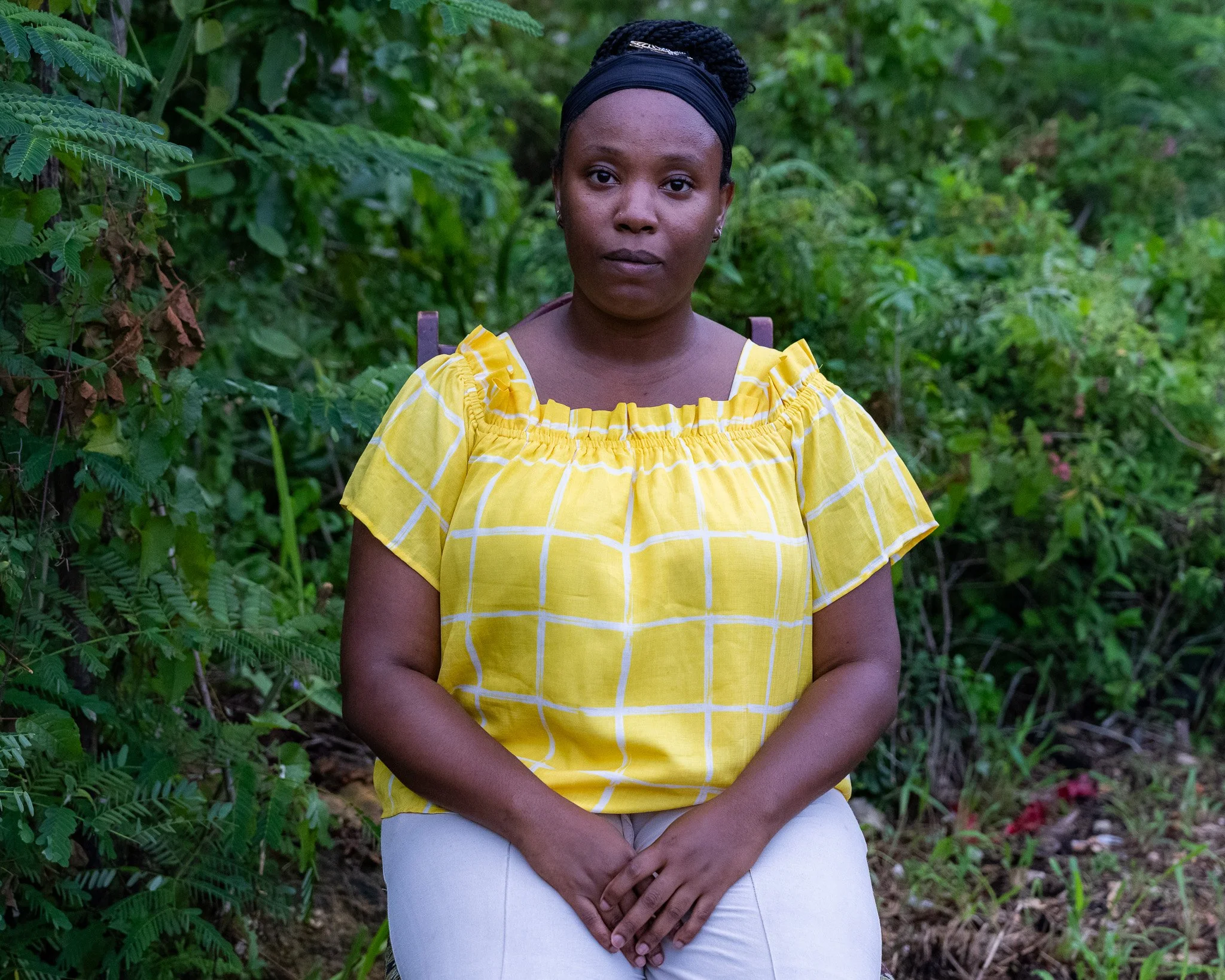 Rashada Azania Elliott, 2nd-generation Rastafari and nurse at a Rastafari elder-care center, seated outdoors in Jamaica.
