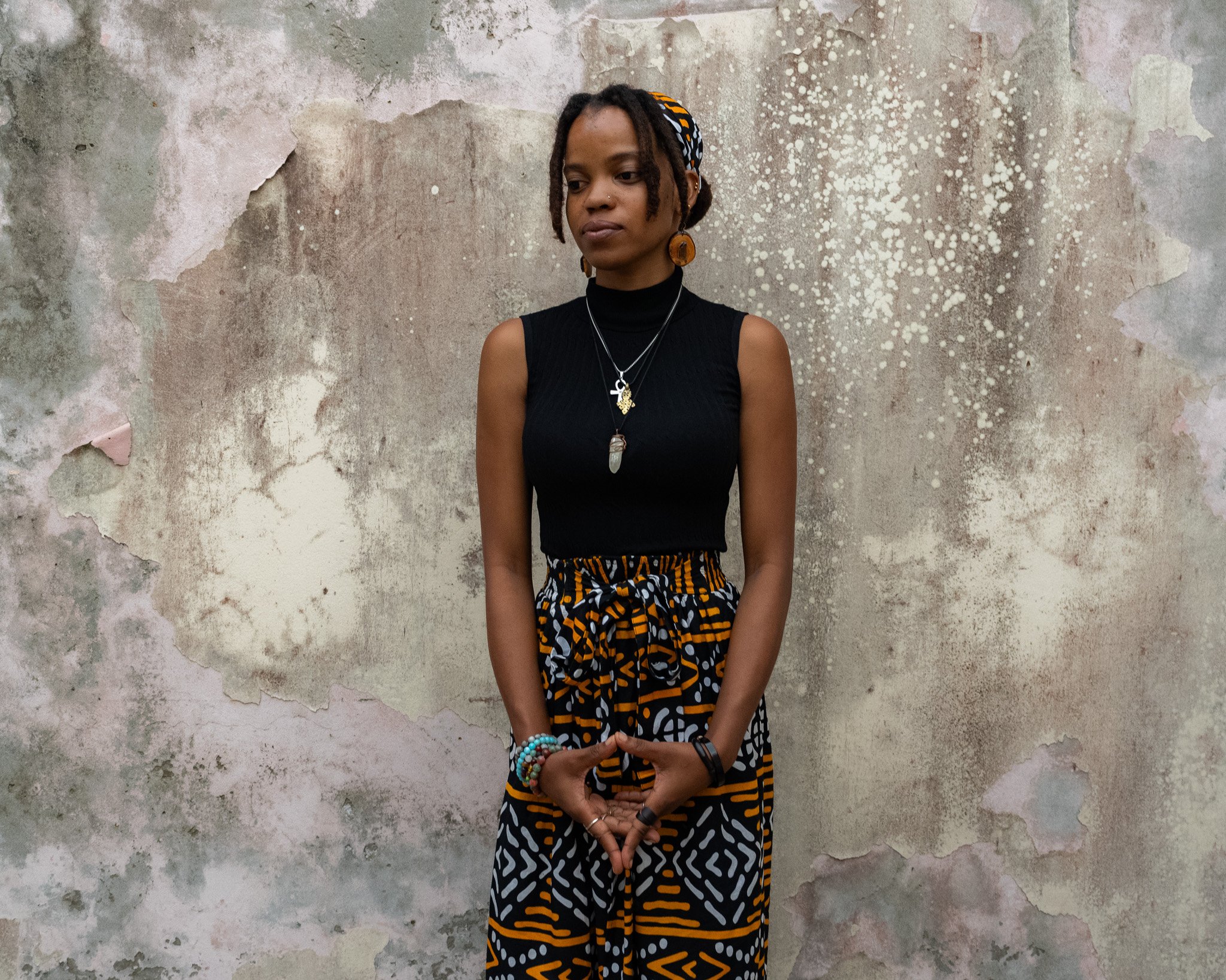 Iyandi Ion, 2nd-generation Rastafari, standing against a weathered wall in Jamaica for a portrait about Rastafari identity and perception.