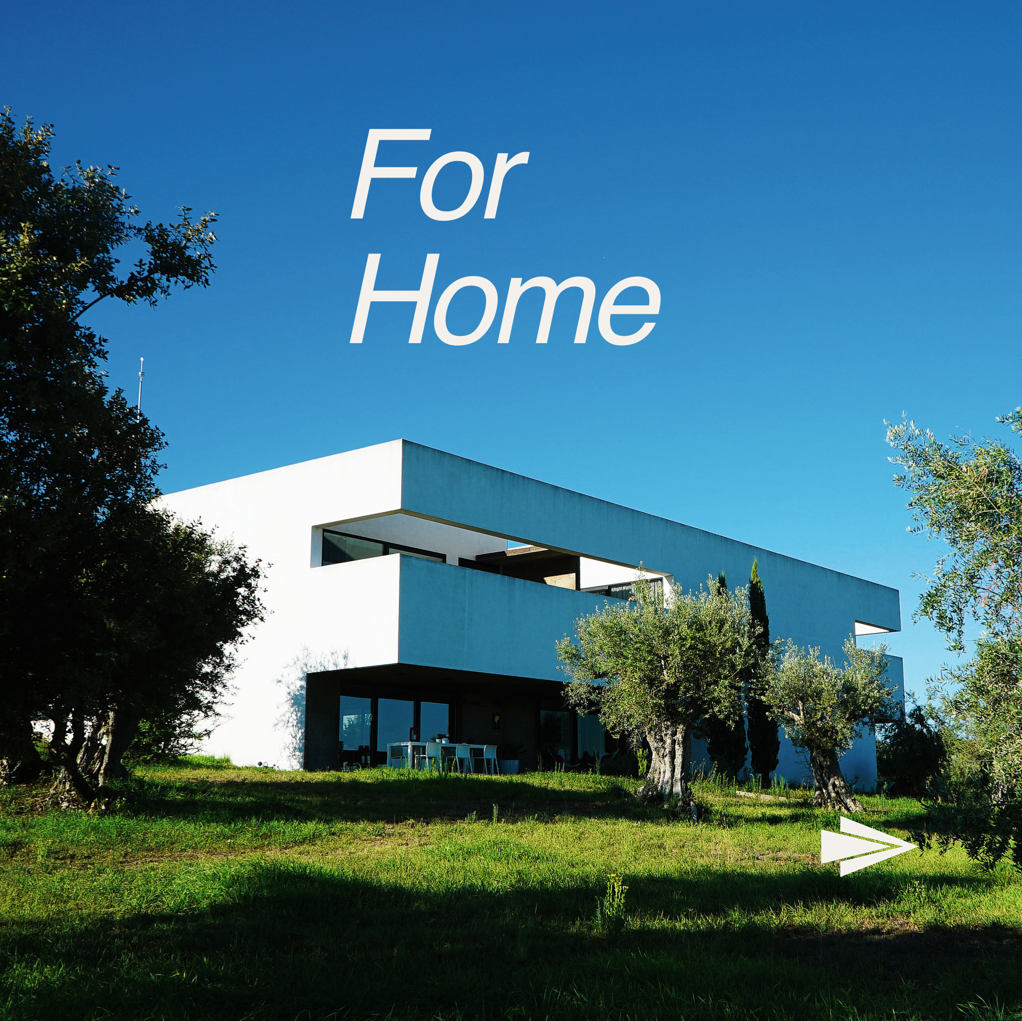 Modern white house with large windows and a balcony, surrounded by trees, under a bright blue sky.