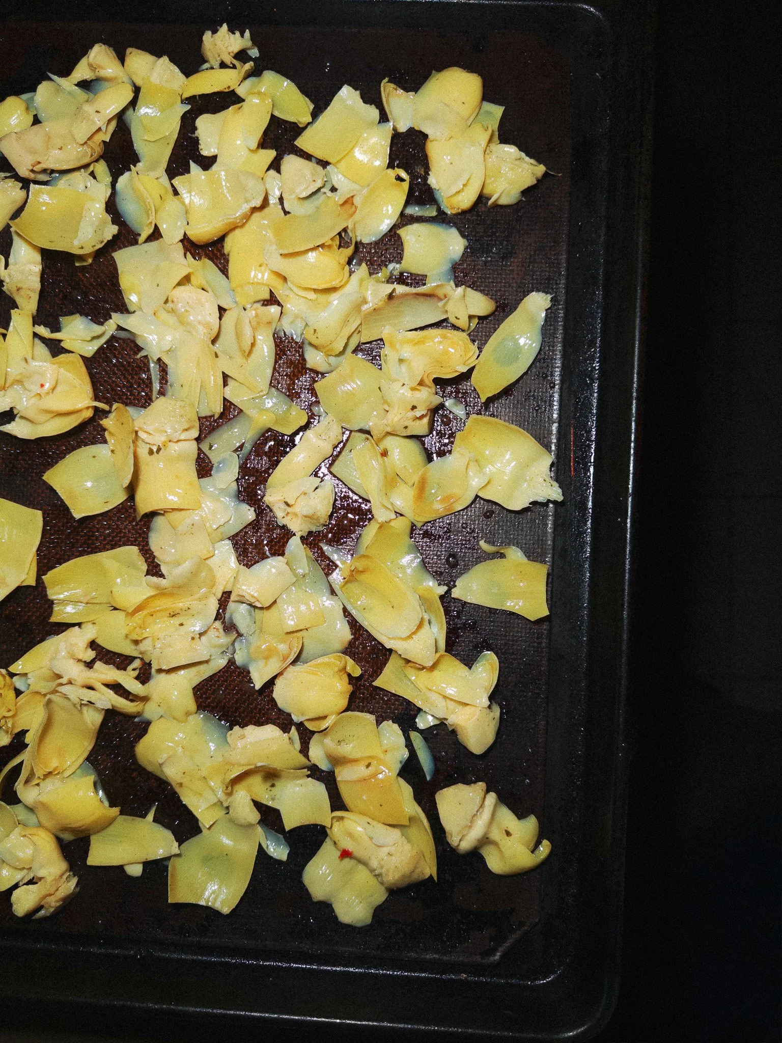 Yellow potato peels on a black oven tray.