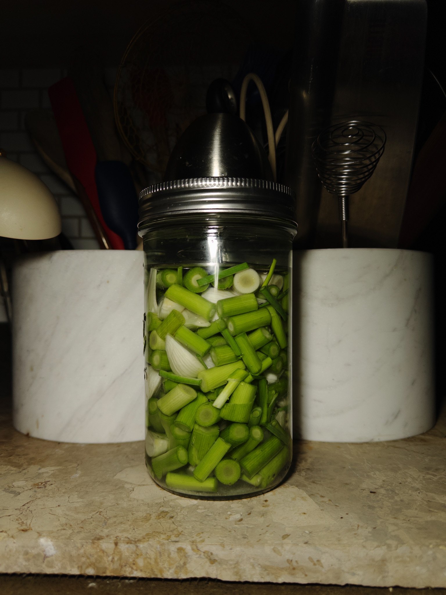 Lacto-fermenting green vegetables in mason jar with fermentation weight during active fermentation process at room temperature
