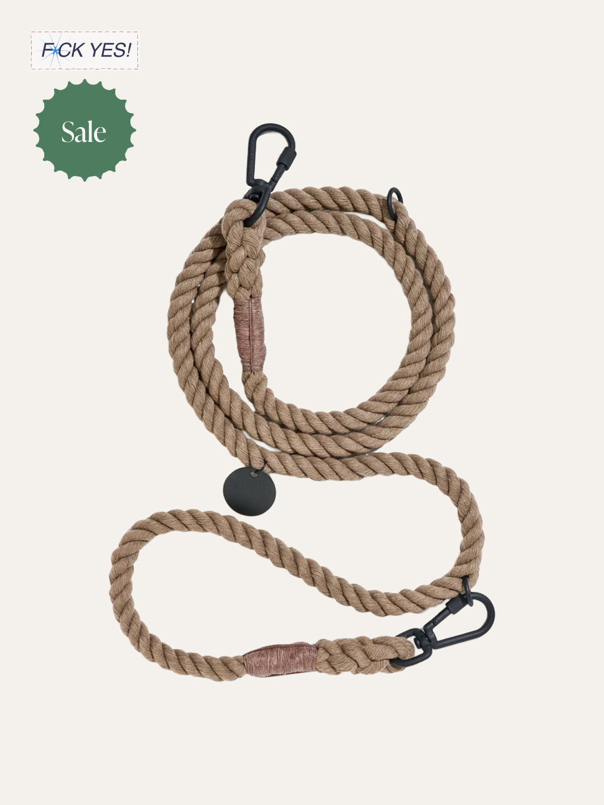 A coiled beige rope with black carabiners on each end, a circular black tag hanging from the middle, and a pink enough section of fabric wrapped around the rope.