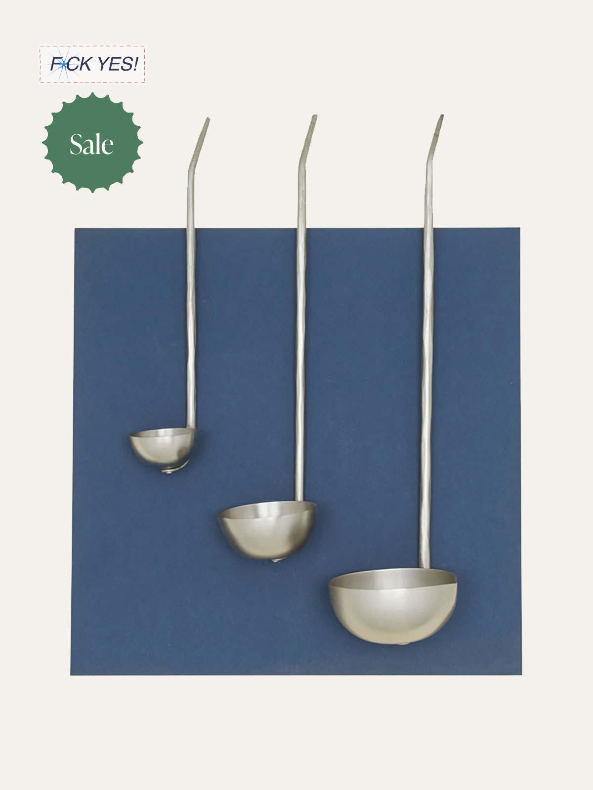Three large stainless steel ladles with long handles are mounted on a display board, with one ladle hanging lower than the others.