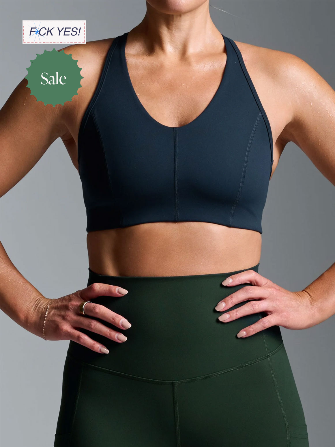 Close-up of a woman in workout attire, wearing a black sports bra and high-waisted leggings, with her hands on her hips.