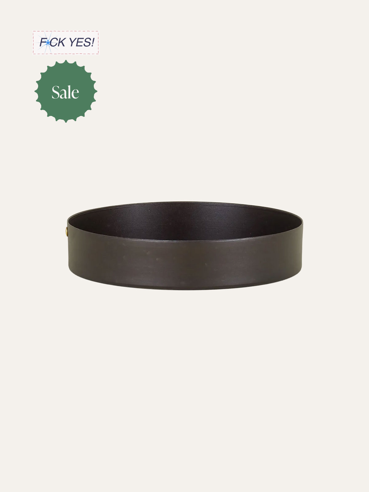 Plain black round tray or tray-like object against a beige background. Green sale tag and a partial 'F*** YES!' text in the top left corner.