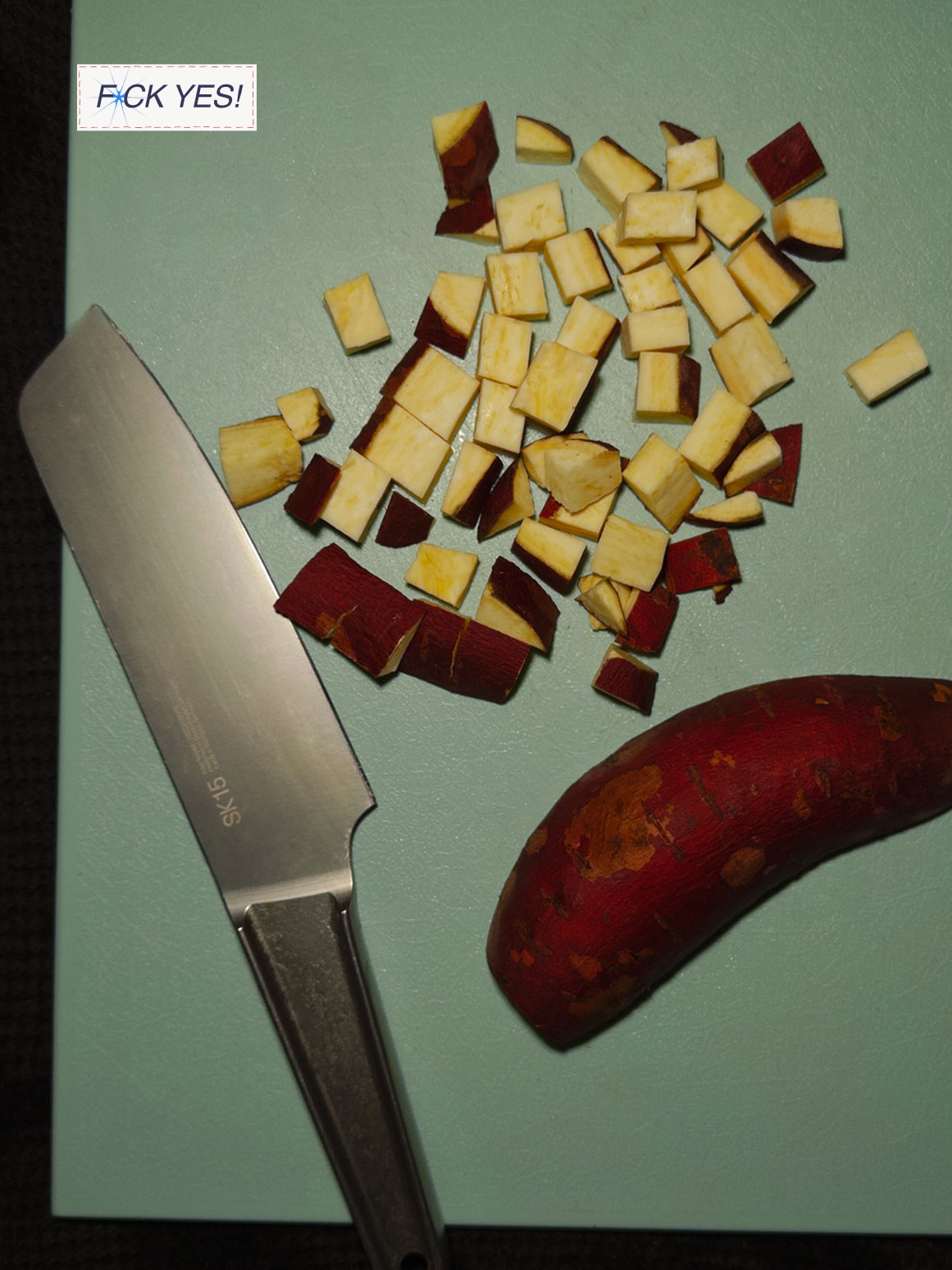 Chopped sweet potato pieces on a cutting board, with a large chef's knife and a whole sweet potato nearby.