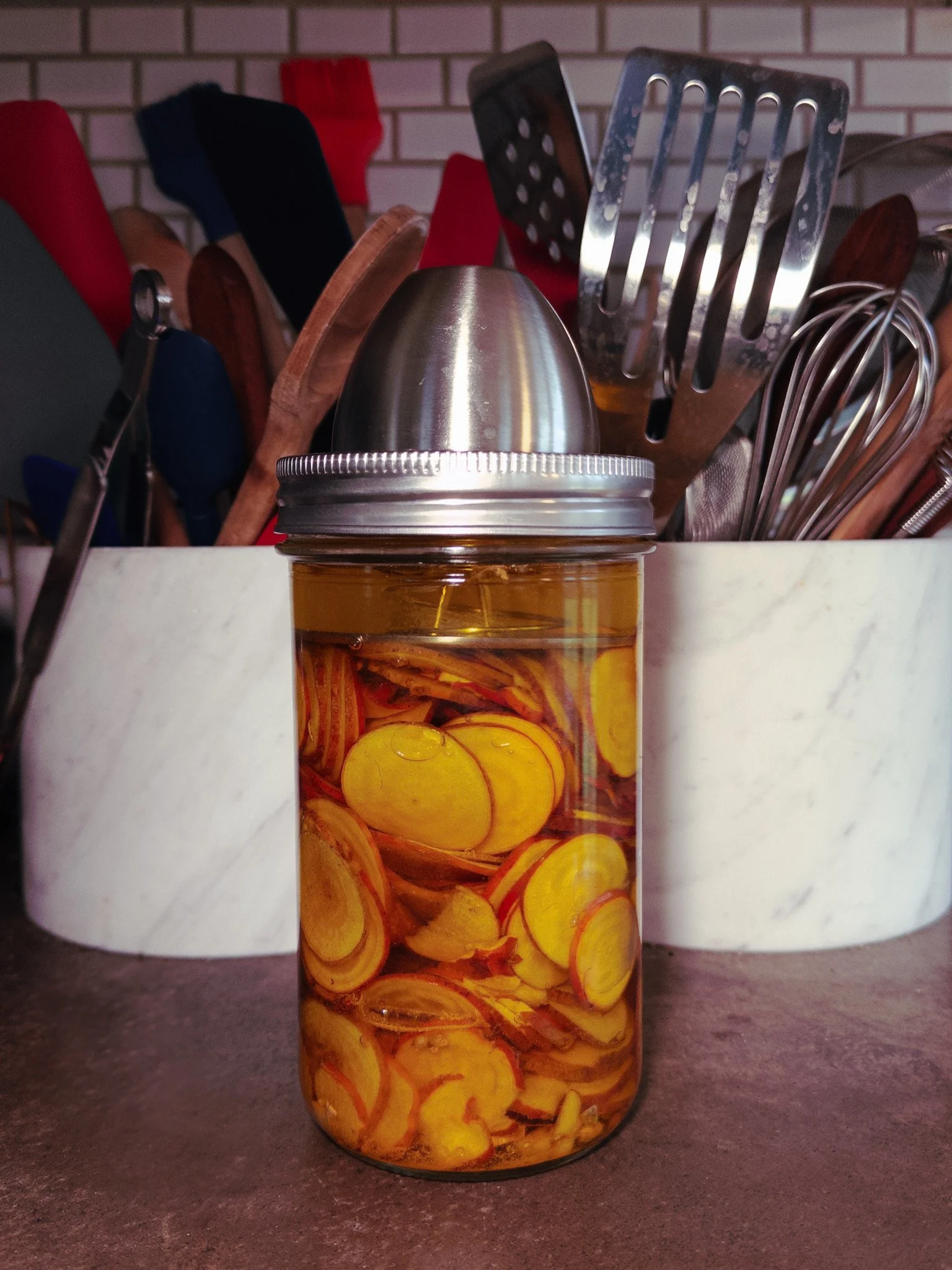 Complete lacto-fermentation setup showing mason jar with golden beet slices, fermentation weight, and kitchen equipment