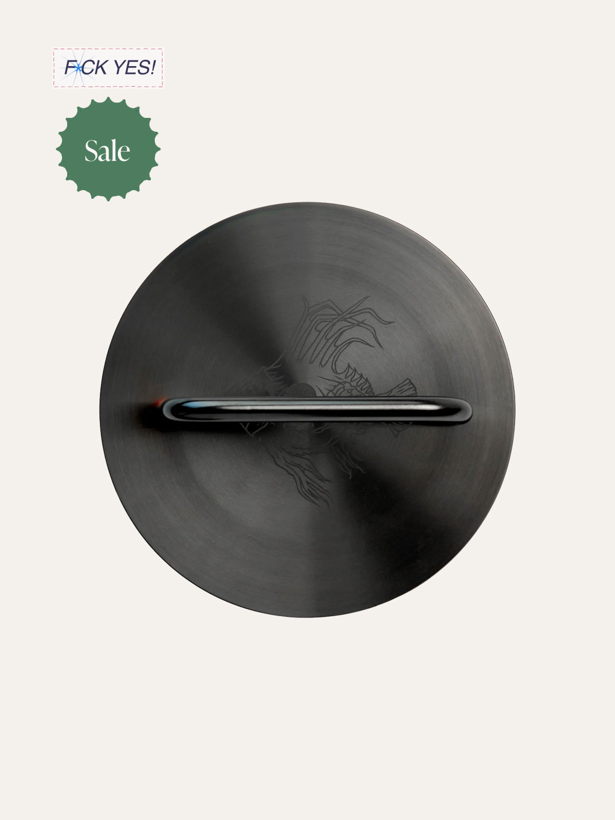 A black circular object with a handle in the center, featuring a faint dragon design engraved on it. The background is plain and light-colored, with sale and promotional stickers in the top left corner.