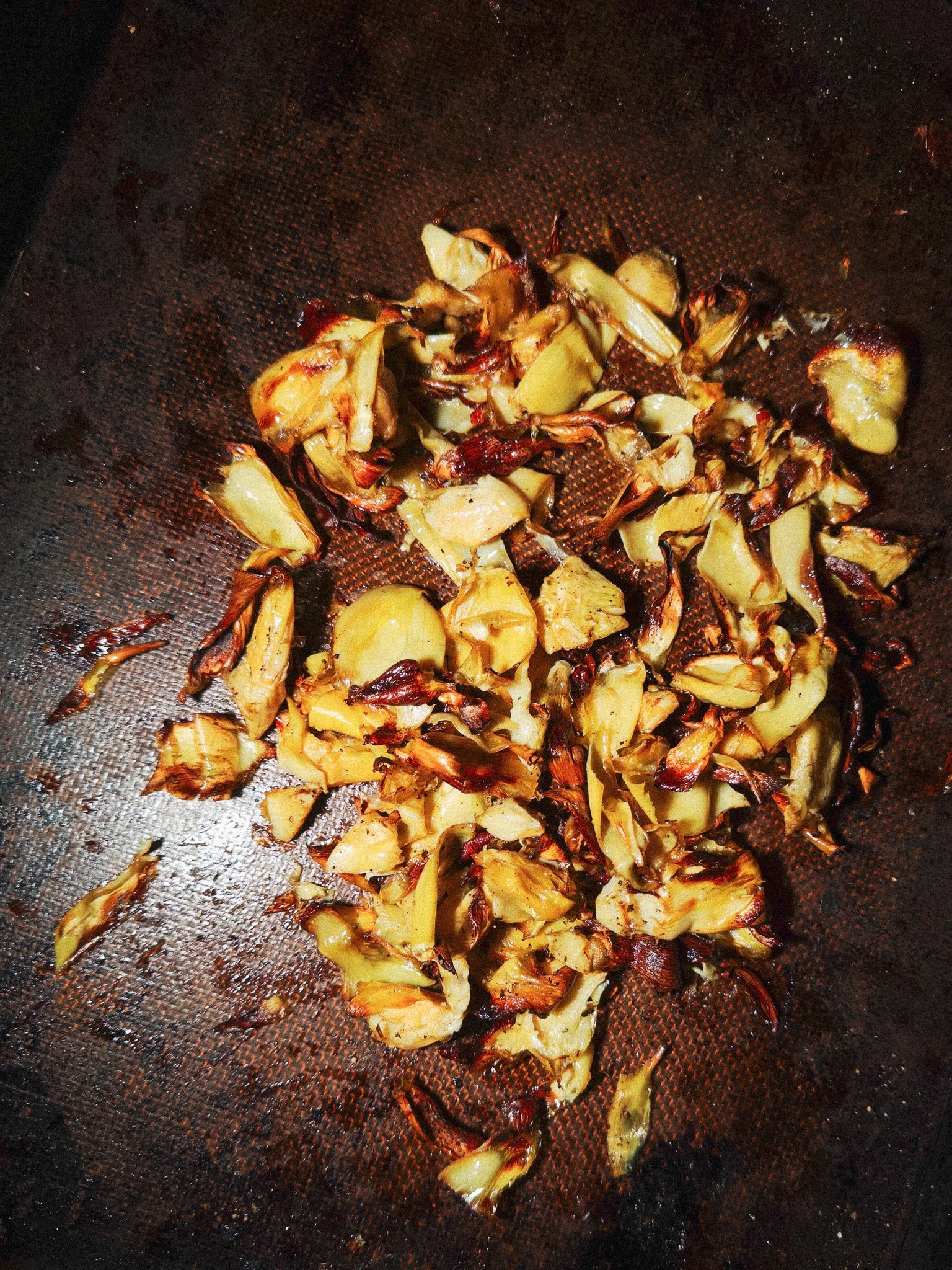 Burned garlic cloves in a black pan.