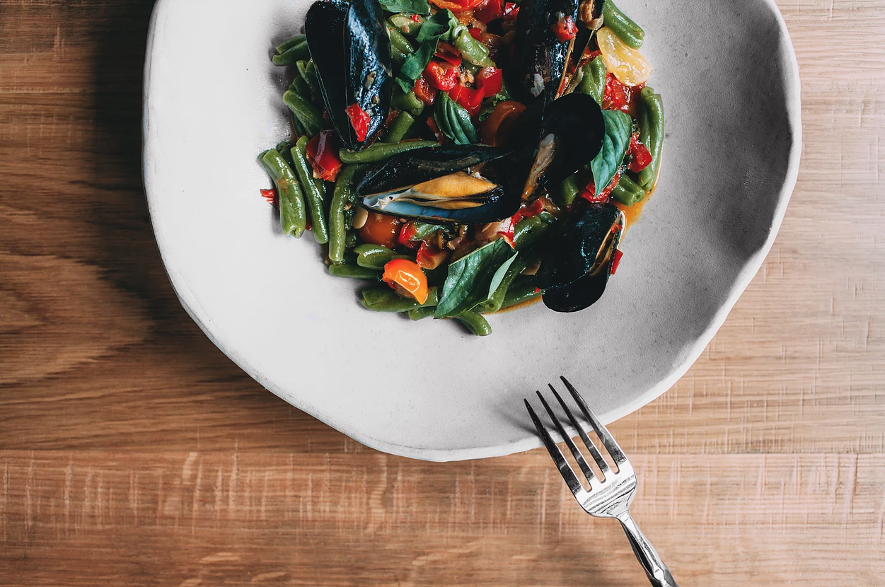  A close-up view of a gourmet dish featuring mussels and handmade pasta, beautifully presented and ready to delight the senses. 