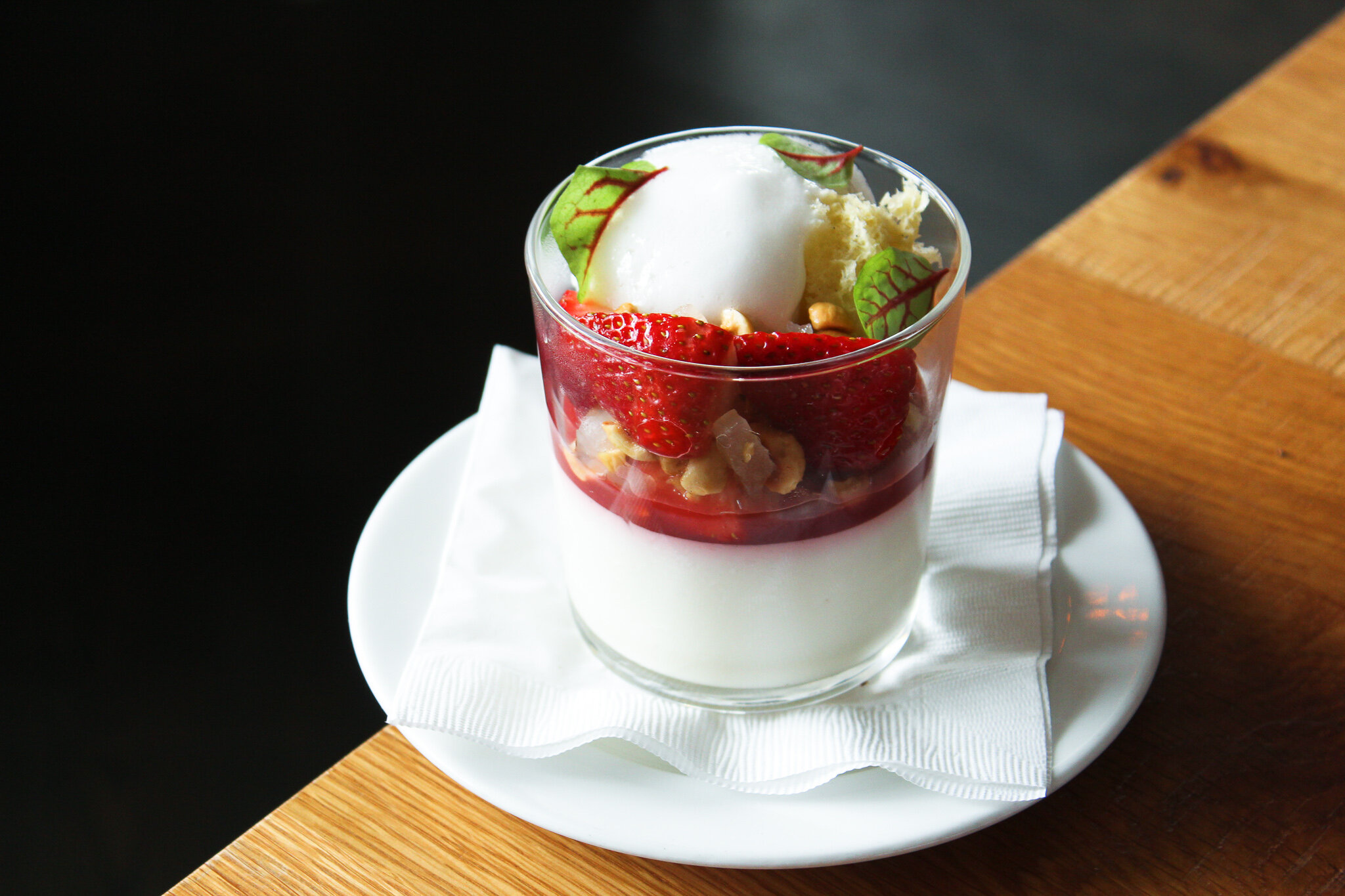  A mouth-watering dessert presentation featuring a parfait with fresh strawberries, nuts, and delectable layers. 