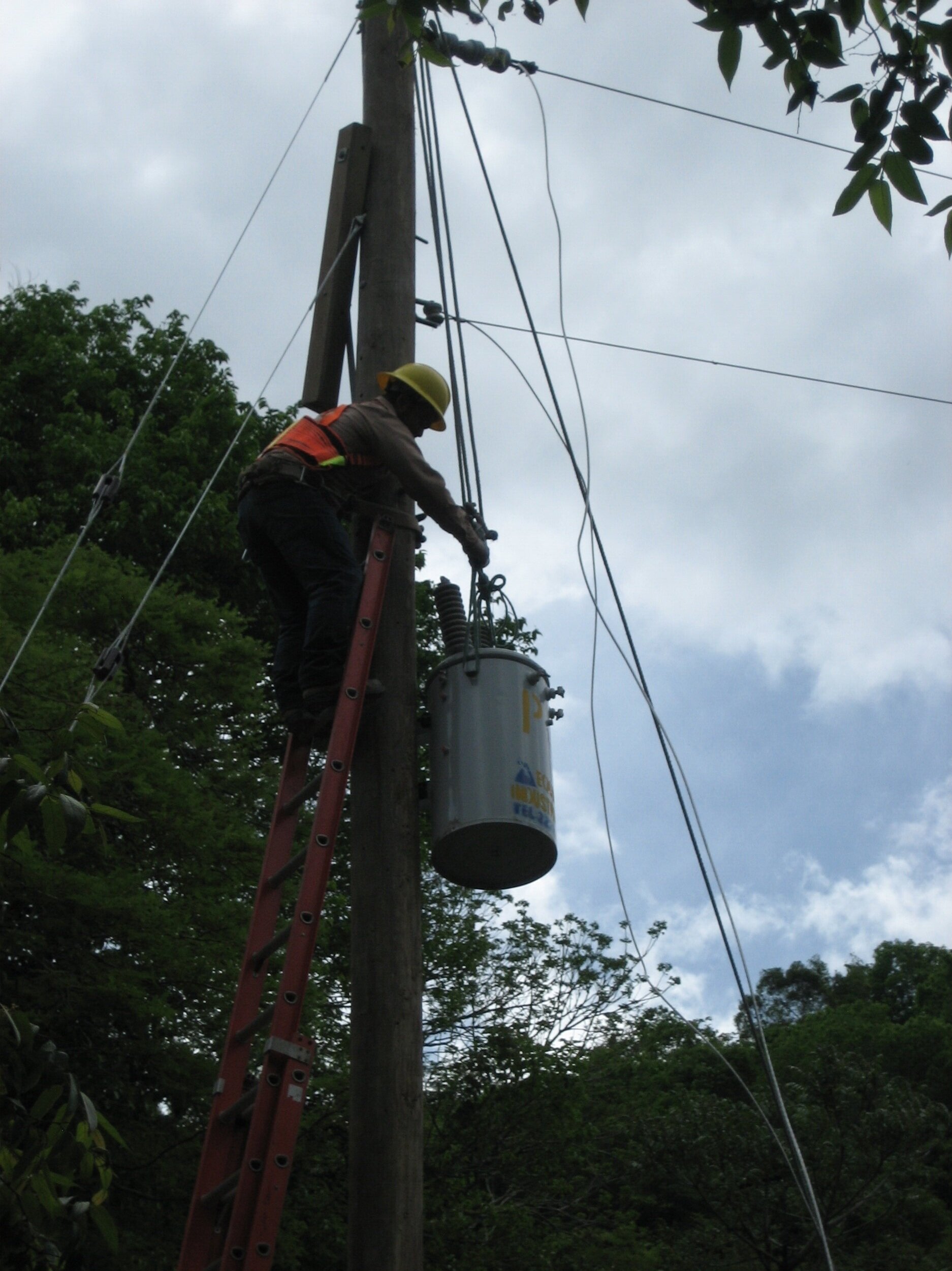 Line workers raise the electrical transformer into place.