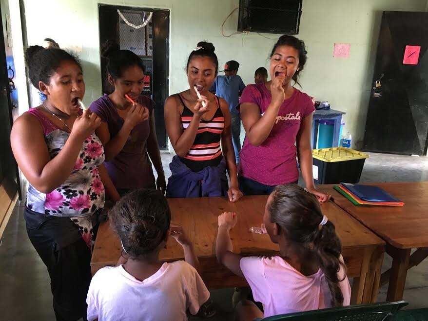 Fuerza girls leading a demonstration on how to properly clean teeth.