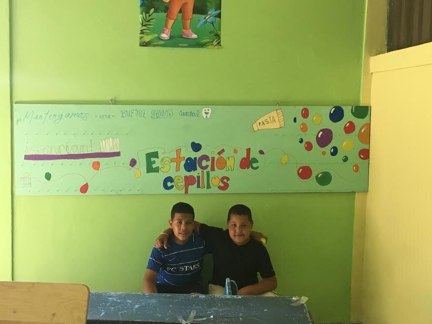 Two Fuerza students pose after hanging a dental station in the El Rosario school. Teachers will build regular health cleaning into the daily schedule.