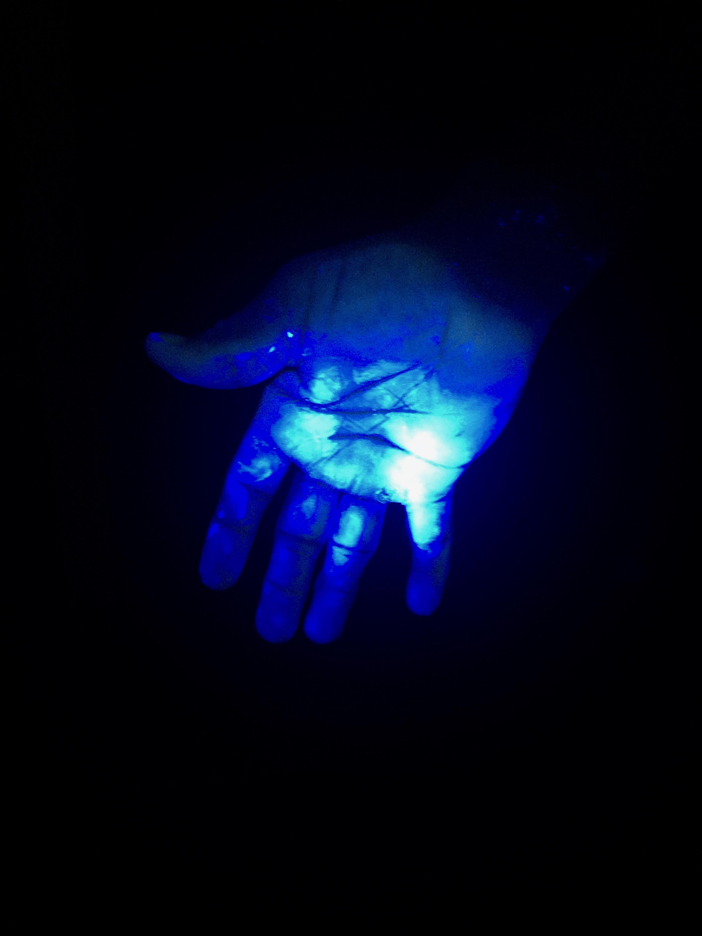A farmer’s hand under UV light showing contamination from applying pesticides.