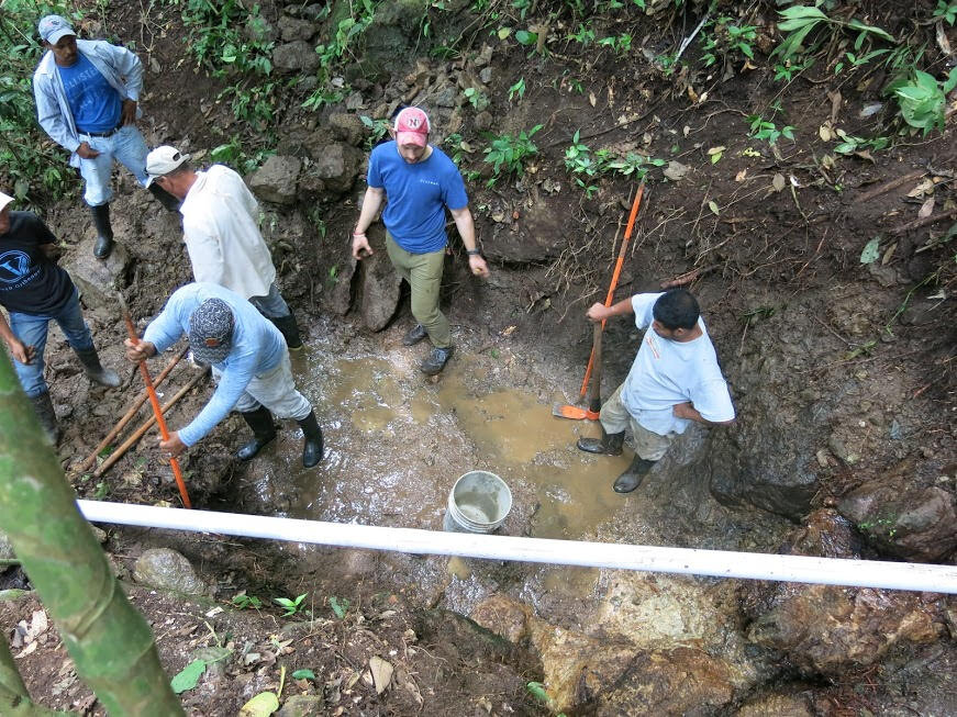 Digging a foundation hole for one of the spring boxes. Most of the water is bypassing the hole through the white pipe spanning the photo.