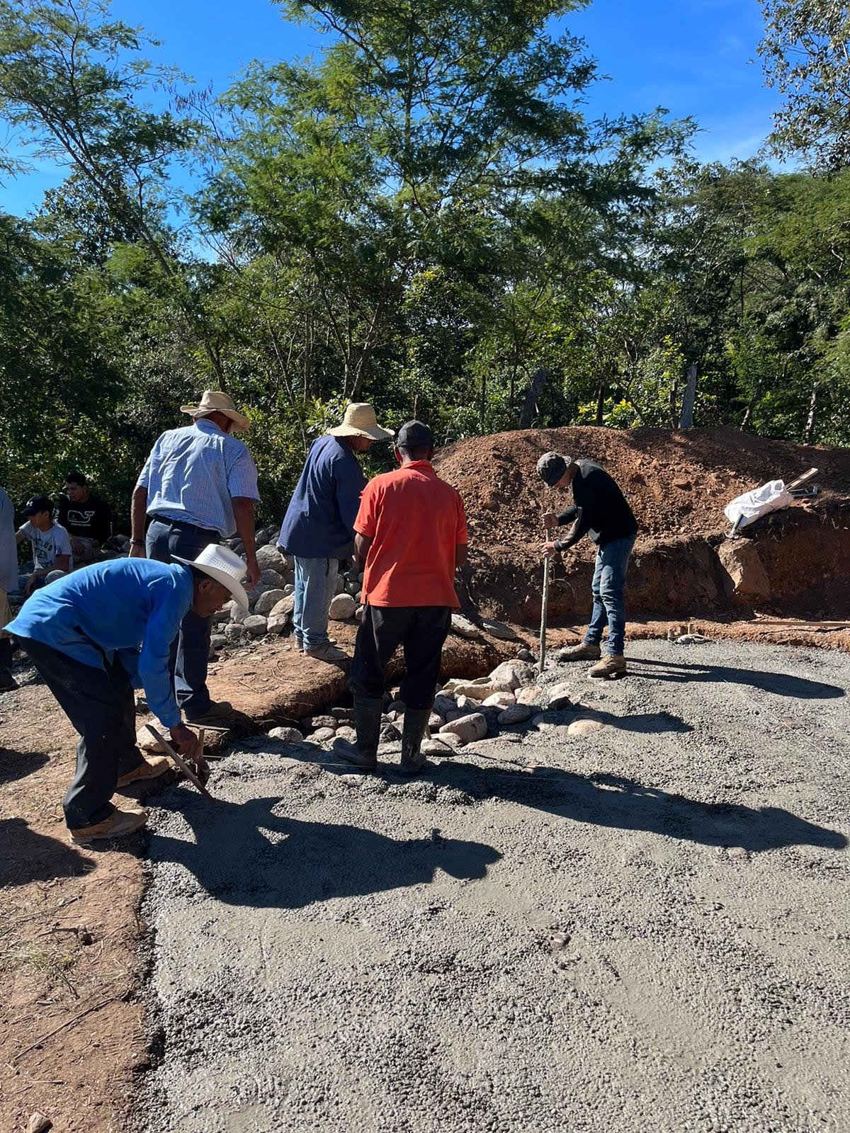 Community members working with a hired mason to build the sub-base for the tank foundation to be built upon.