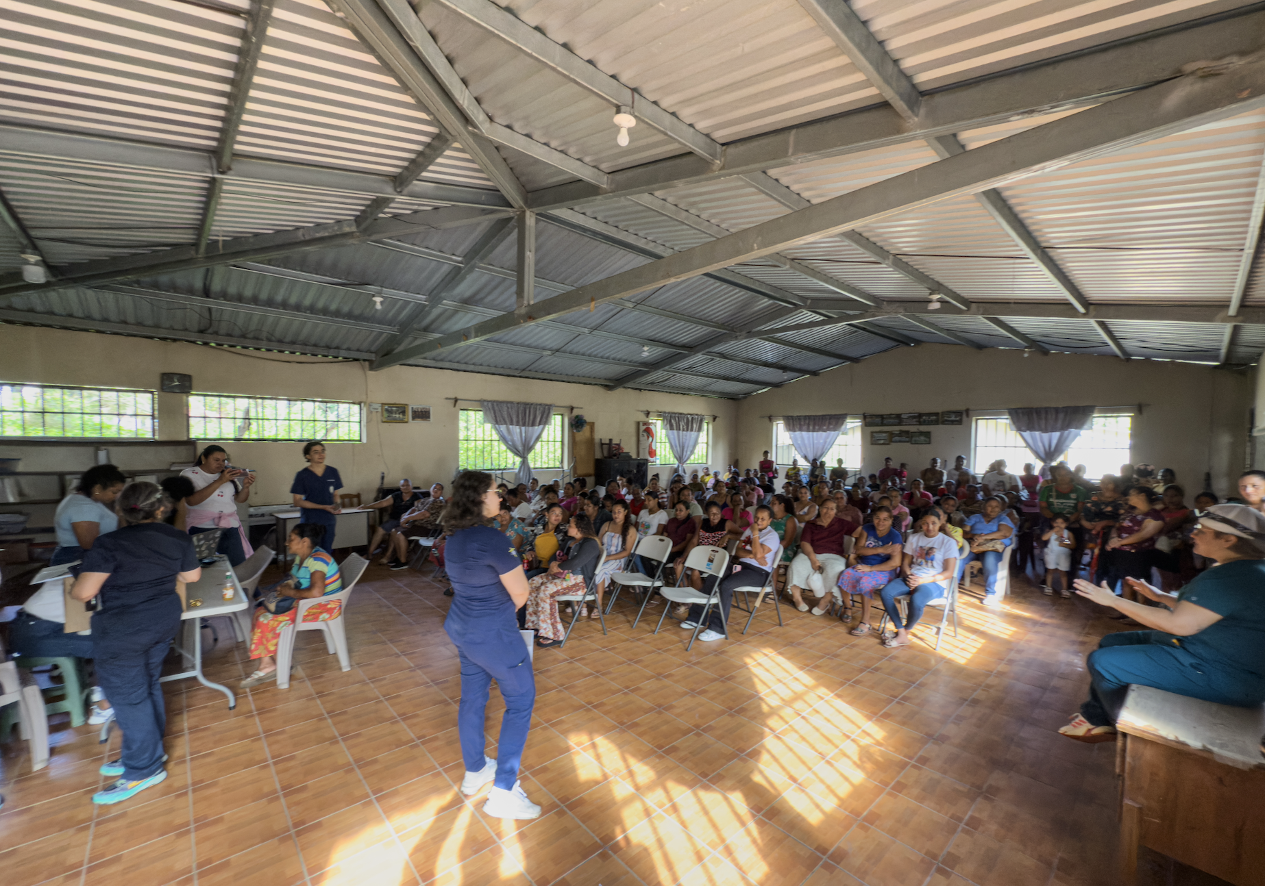 Cancer screening for 350 in one day requires planning and precision. To keep people coming back next time, the participants are treated gently and with great kindness. In this photo, while they wait to check in, they listen to a talk on how to do a b