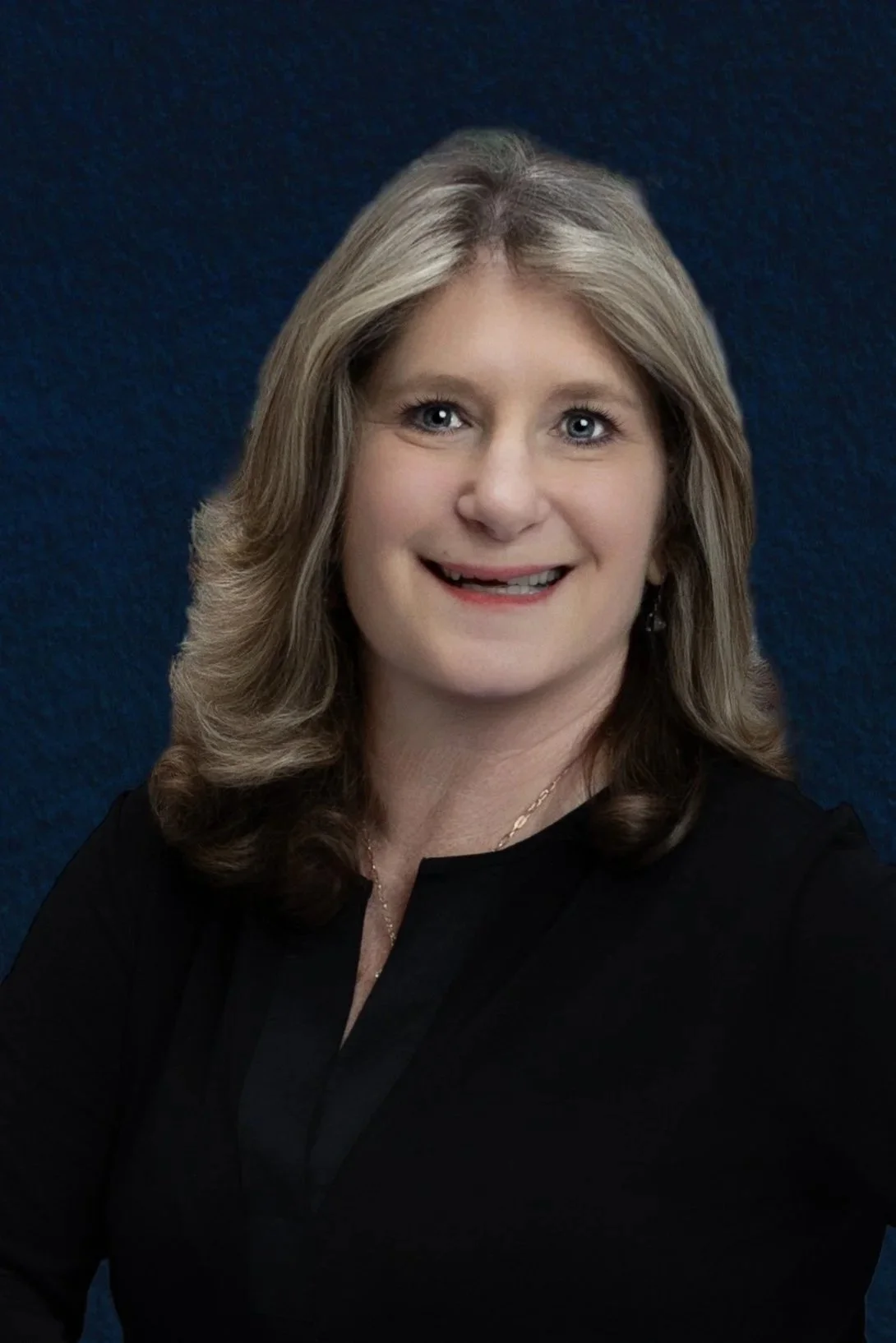 A woman with blonde hair and blue eyes smiling, wearing a black top, against a dark blue textured background.