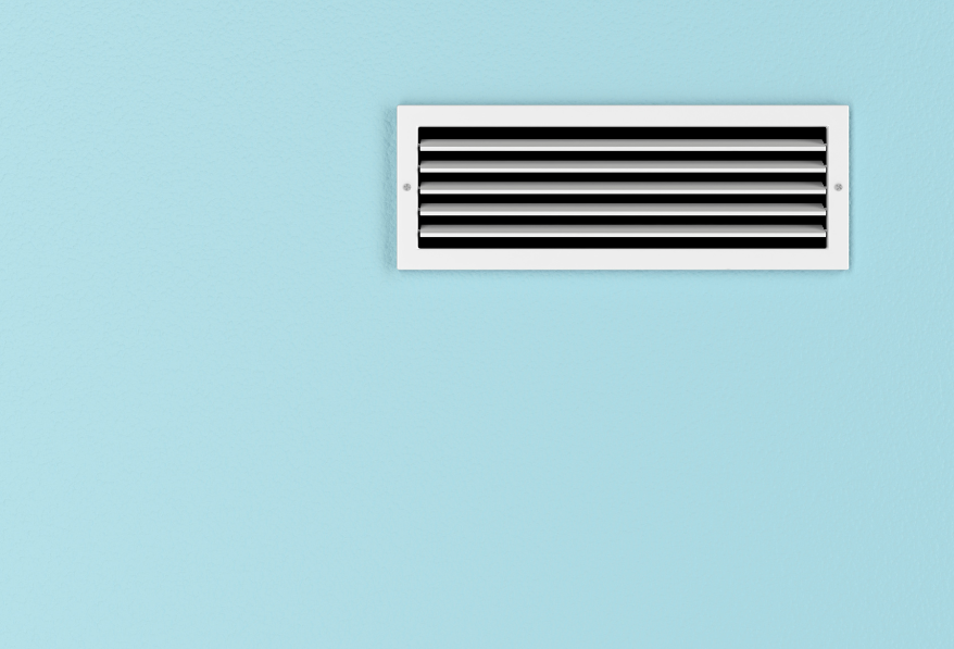 Wall vent with white grille against light blue background.