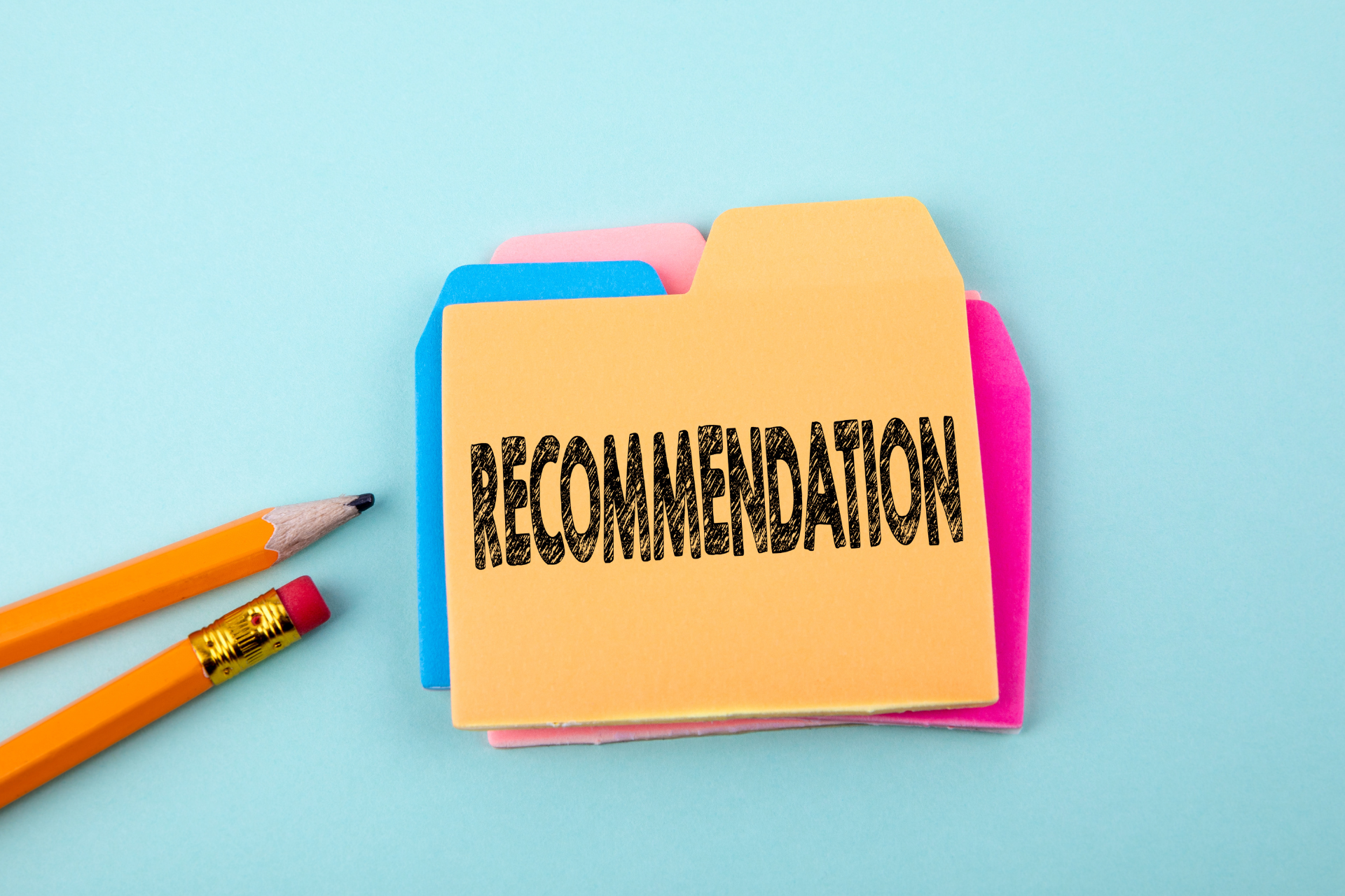 Yellow folder labeled 'Recommendation' next to pencils on a blue background.