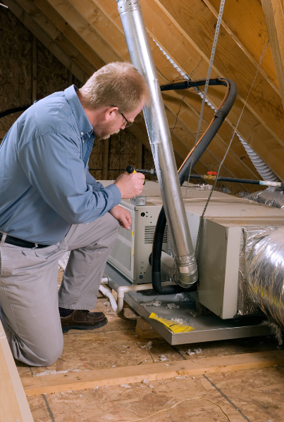 Technician inspecting HVAC unit in attic