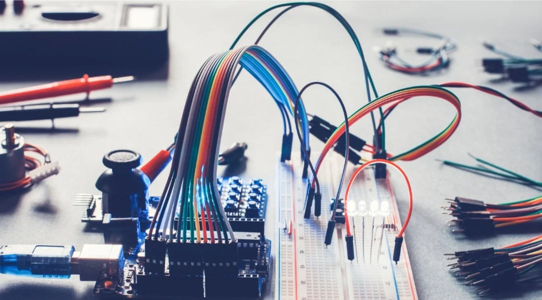 Circuit board with connected wires, LEDs, and electronic components on a table.