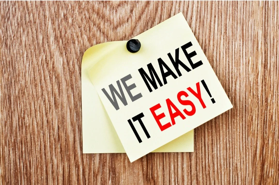 Sticky note with the text 'We Make It Easy!' pinned to a wooden surface.