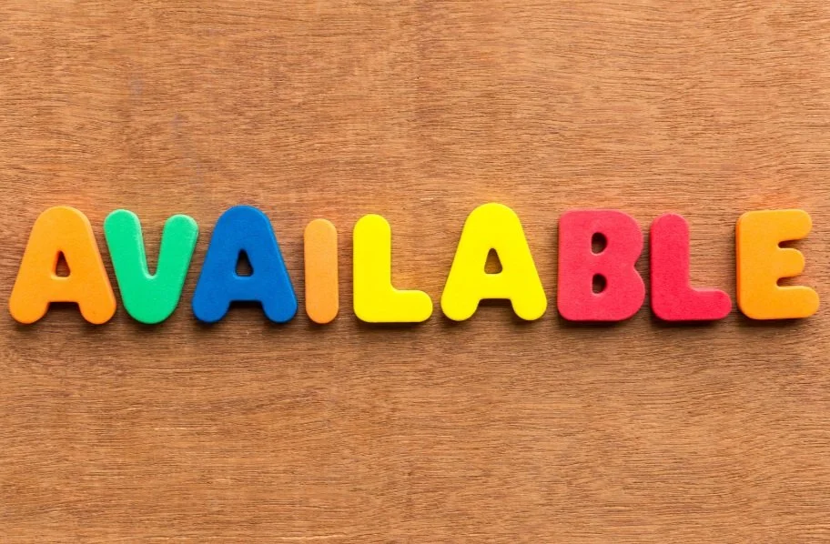 Colorful foam letters spelling "AVAILABLE" on a wooden background.