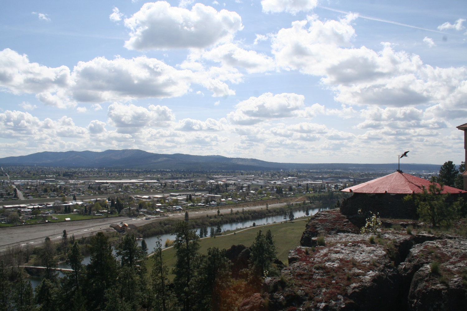 a landscape photo with a beautiful blue sky, low mountains, a small city, and a river