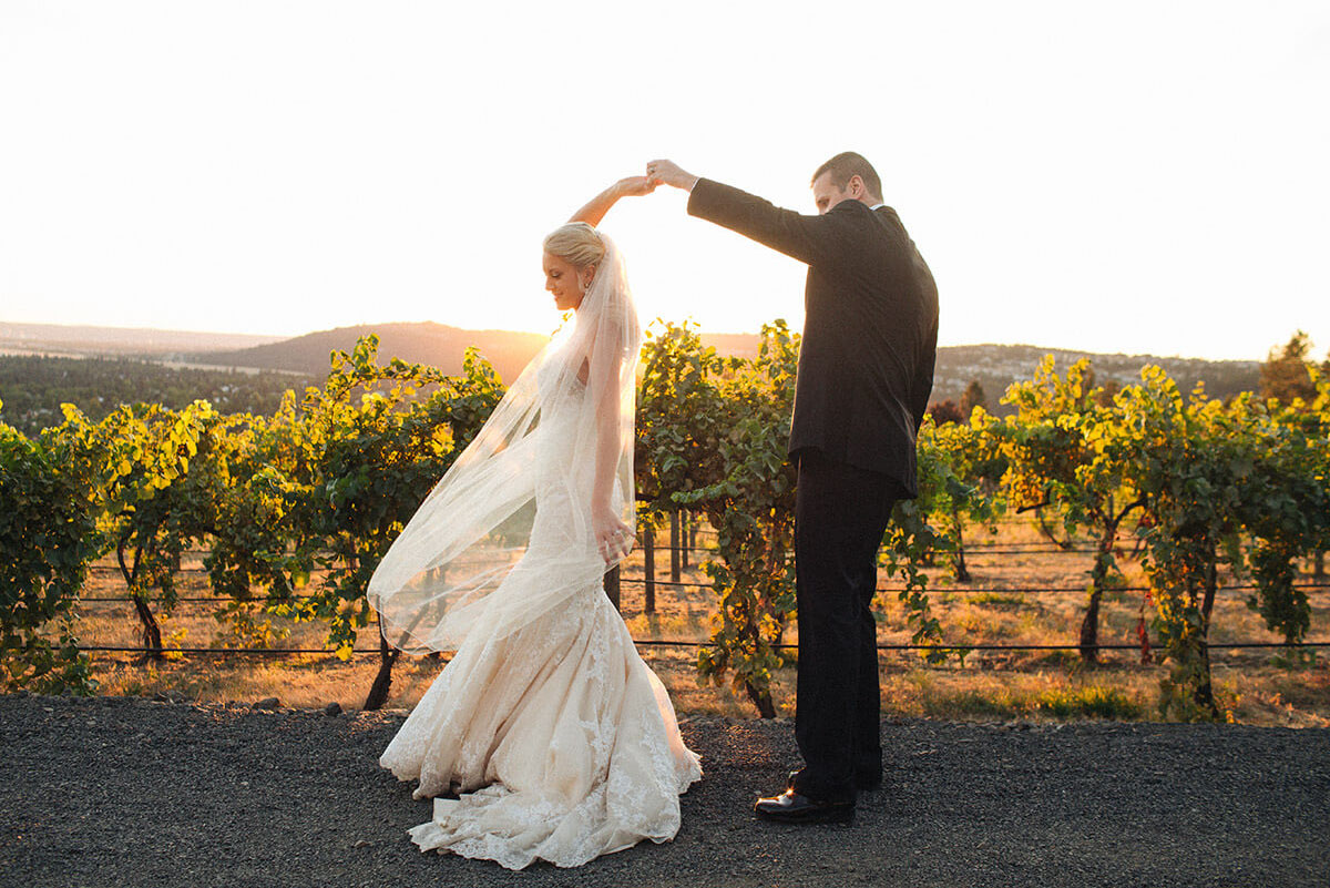 A photo of a bride and groom dancing in front of a vineyard