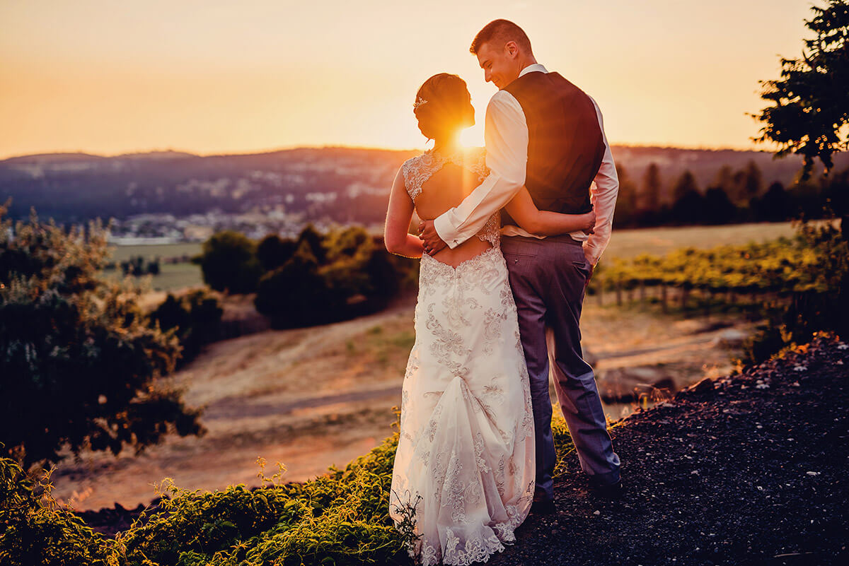 A photo of a bride and groom holding each other in front of a beautiful sunset