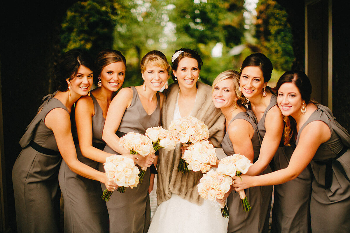 A photo of a bride and her bridesmaids holding their flowers in the center of the group