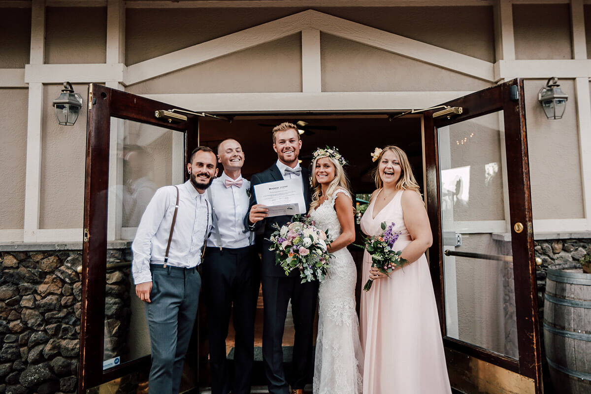 A photo of a group of happy people on a wedding day with open doors behind them